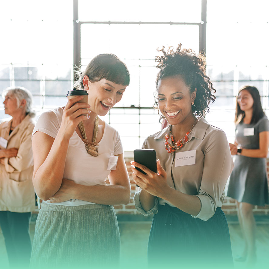 Two smiling women looking at contacts on phone