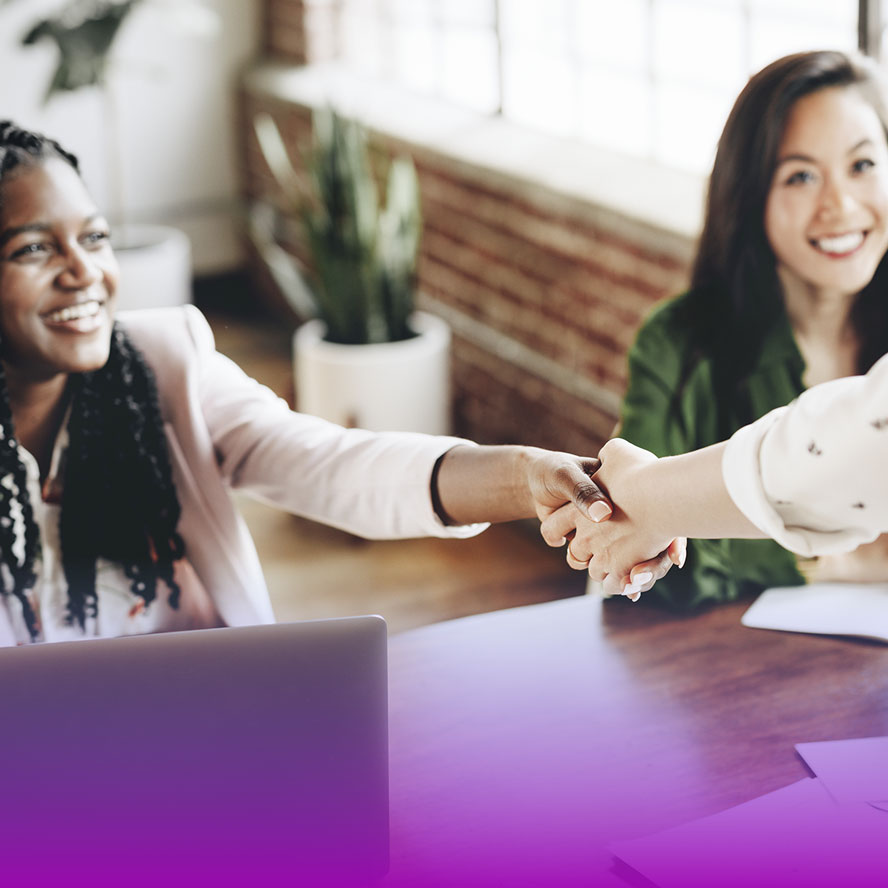 Two people shaking hands while third looks on